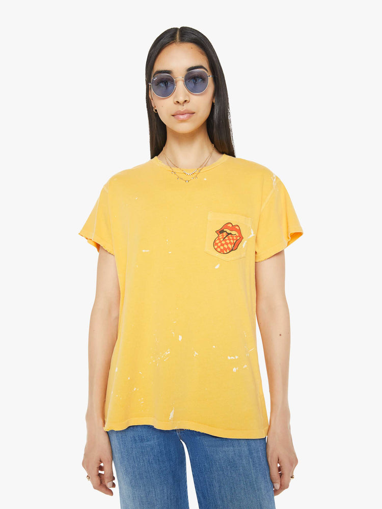 Front view of a woman tee in golden-yellow, the tee honors the Rolling Stones with the band's iconic tongue-and-lips logo on the front and a checker-print graphic on the back.