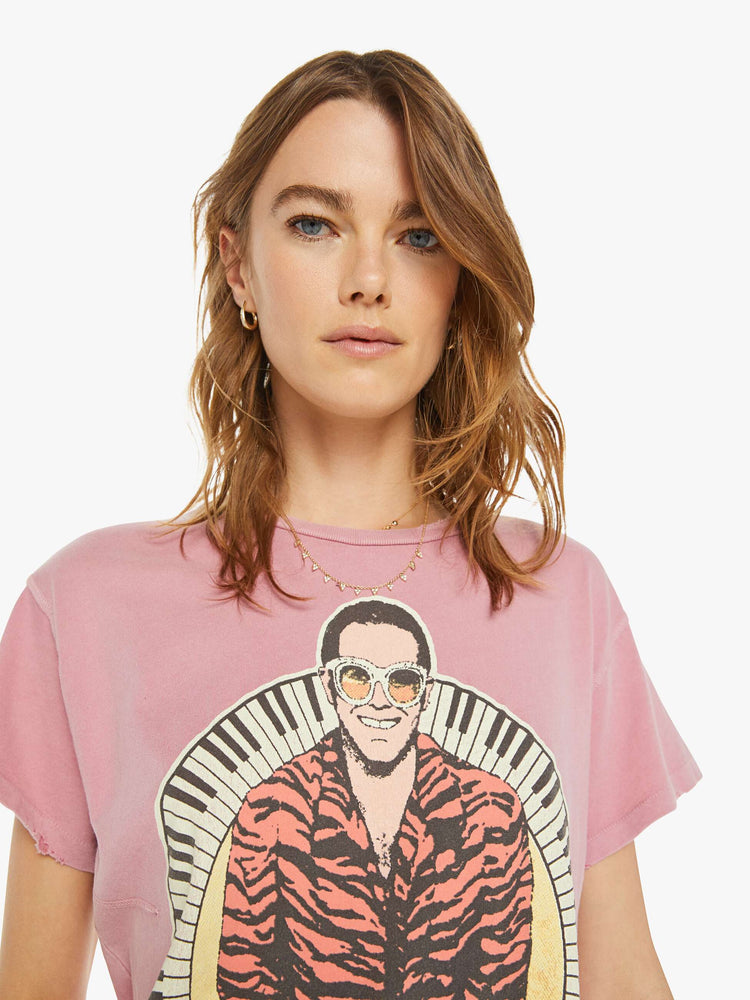 Close up view of a woman tee that pays homage to the British musician, Elton John, with bold text and a graphic portrait on the front.