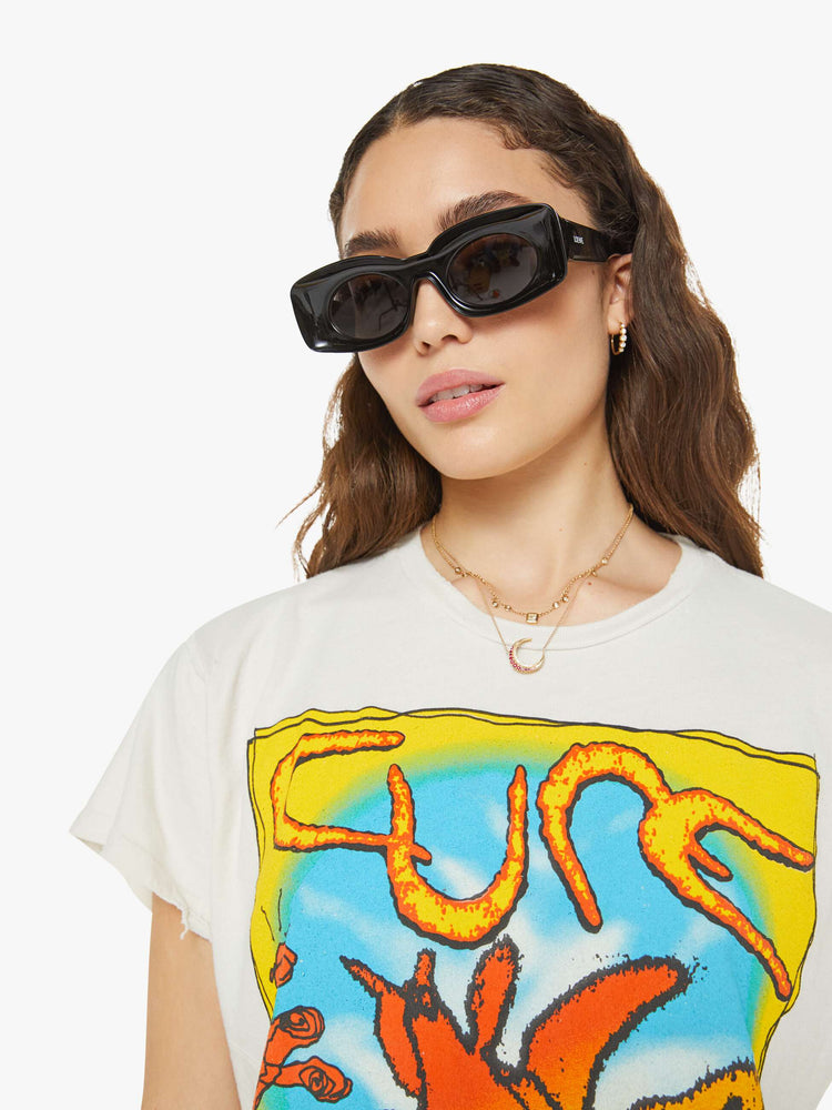 Close up view women in a white tee pays homage to the The Cure with a colorful text graphic on the front.