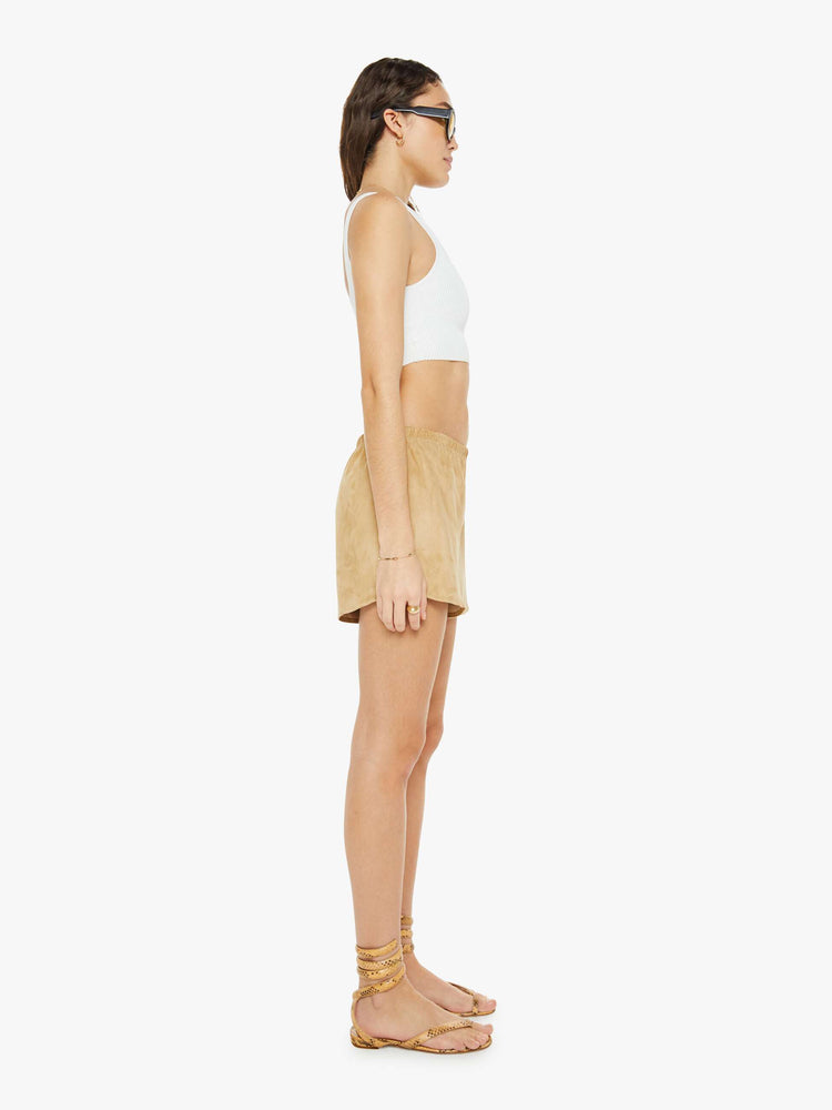Side view of a woman in a leather light khaki shorts with slit pockets and a relaxed fit.