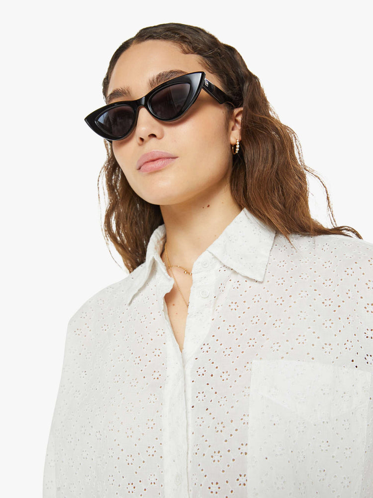 Close up view of a woman white button up blouse with drop shoulders and a cropped, boxy fit.