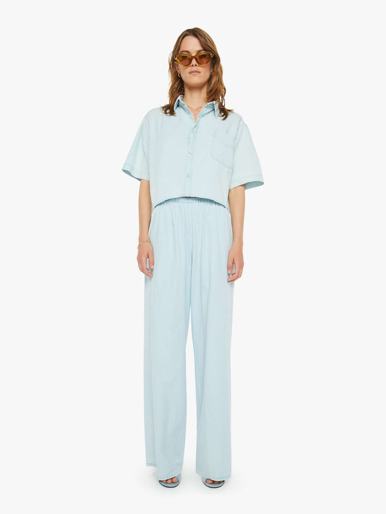 Full body  view of a woman sky blue button-up blouse with a patch pocket, drop shoulders and a cropped, boxy fit.
