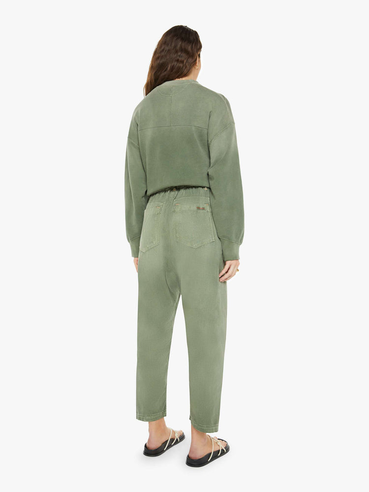 Back view of a woman in a faded army green, the pants have a mid rise, narrow straight leg, drawstring waist with a woven belt and a loose fit.