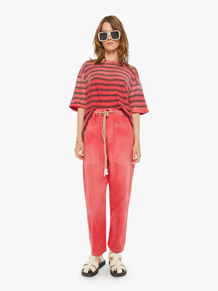Front view of a woman red pants have a mid rise, narrow straight leg, drawstring waist with a woven belt and a loose fit.