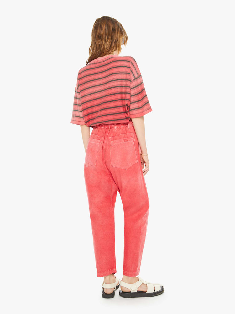 Back view of a woman red pants have a mid rise, narrow straight leg, drawstring waist with a woven belt and a loose fit.