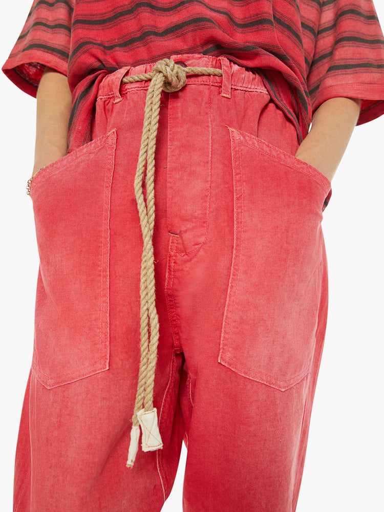 Close up view of a woman red pants have a mid rise, narrow straight leg, drawstring waist with a woven belt and a loose fit.