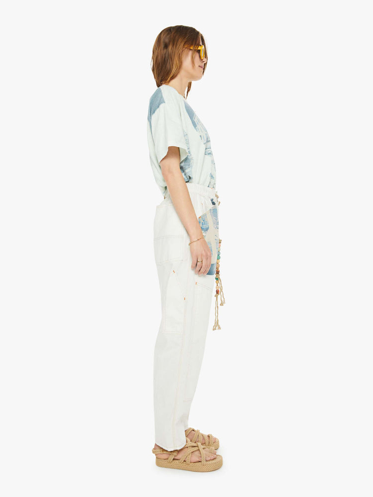 Sideview of a woman pants have a mid rise, straight leg, drawstring waist with a woven belt and a loose fit.