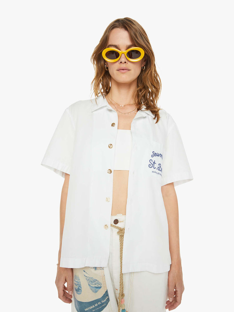 Front view of a woman in a white  with blue embroidery on the chest short sleeve shirt features drop shoulders, boxy sleeves and a loose fit.