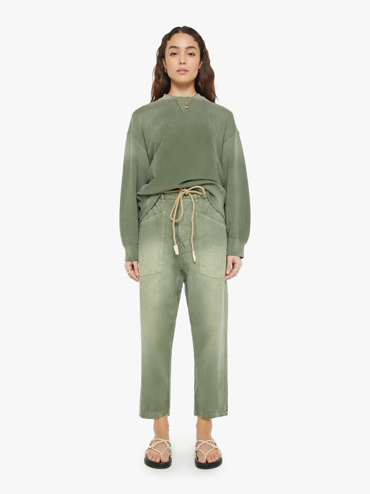 Full body view of a woman in a sweatshirt that features drop shoulders, long, oversized sleeves, ribbed hems and a loose fit. It's made from 100% cotton French terry in olive green.