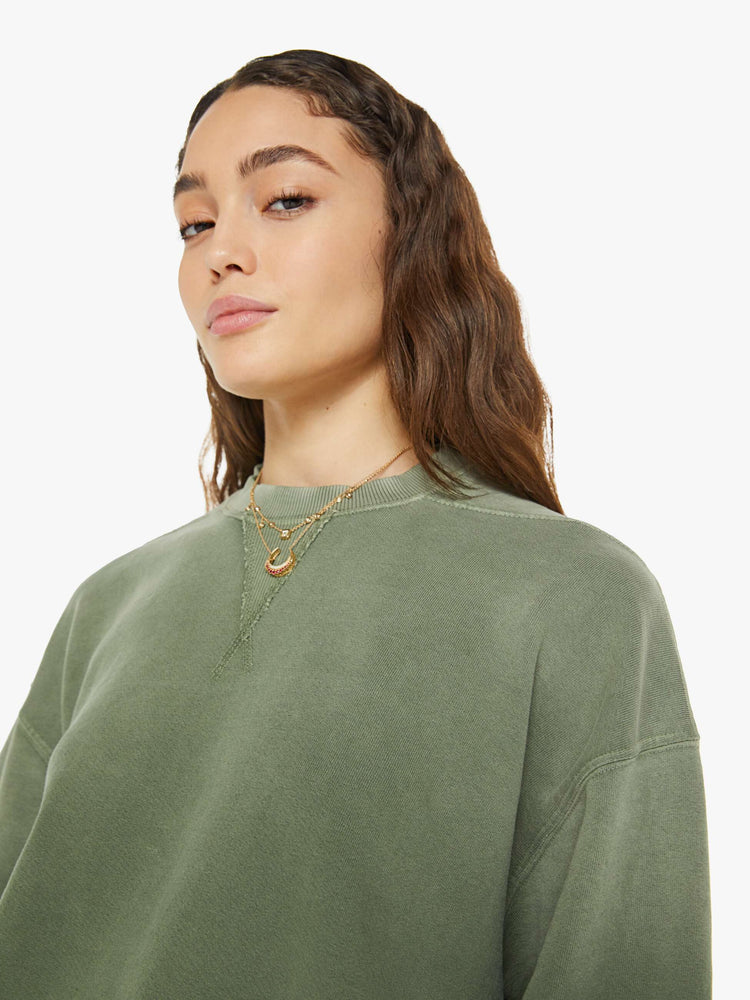 Close up view of a woman in a sweatshirt that features drop shoulders, long, oversized sleeves, ribbed hems and a loose fit. It's made from 100% cotton French terry in olive green.