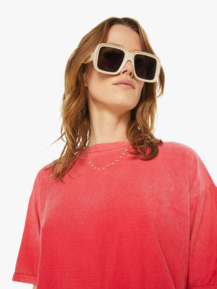 Close up view of a woman in drop shoulders, short sleeves and a boxy fit tee in a faded red.