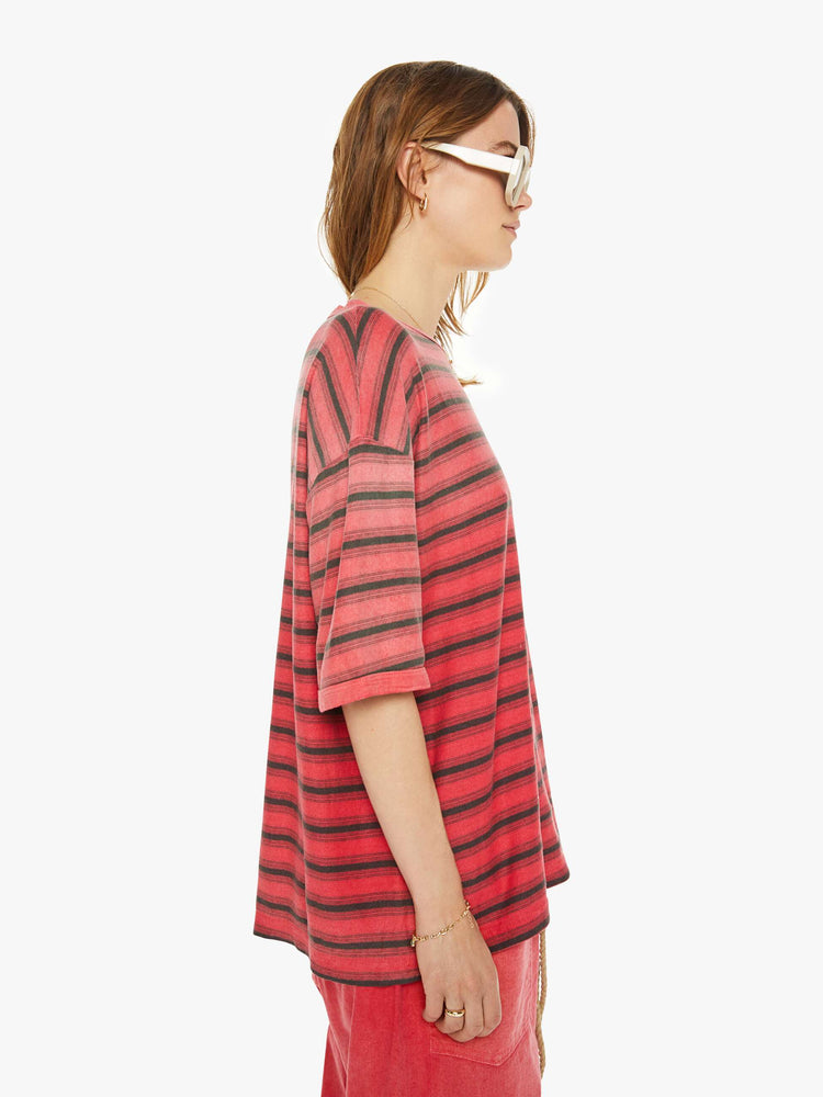 Side view of a woman drop shoulders, short sleeves and a boxy fit in red with navy stripes.