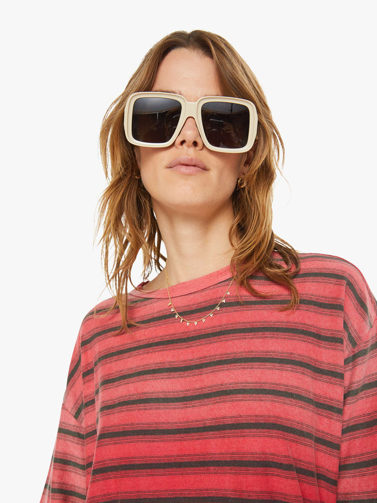 Close up view of a woman drop shoulders, short sleeves and a boxy fit in red with navy stripes.