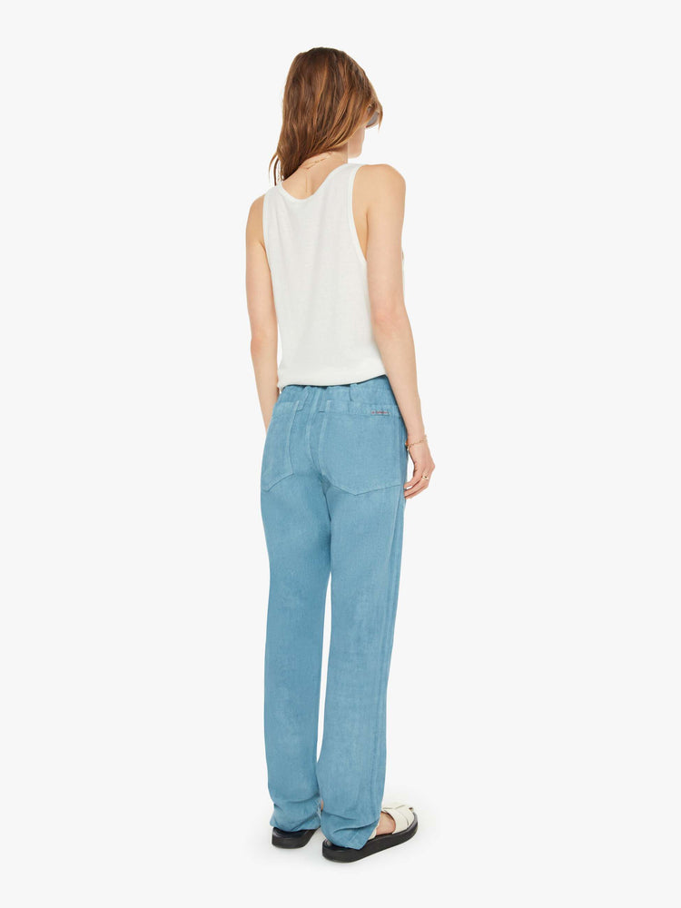 Back view of a woman teal blue pants have a mid rise, narrow straight-leg, patch pockets, drawstring waist with a woven belt and a loose fit.