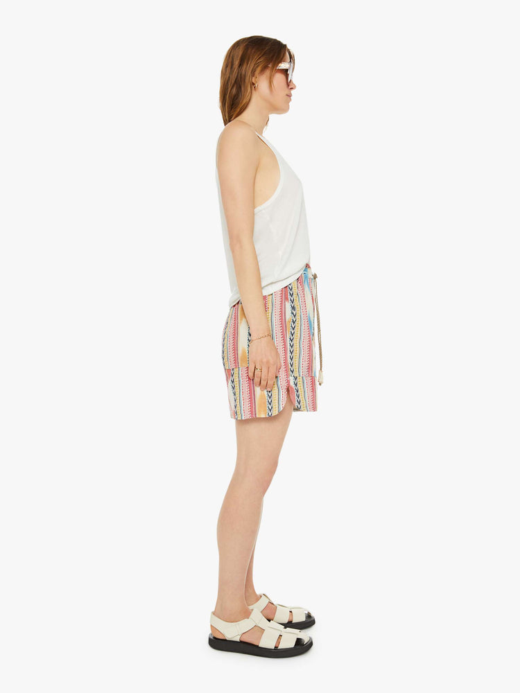 Side view of a woman in shorts have a mid rise, drawstring elastic waist, deep patch pockets, a loose fit and a long inseam that hits just above the knee.