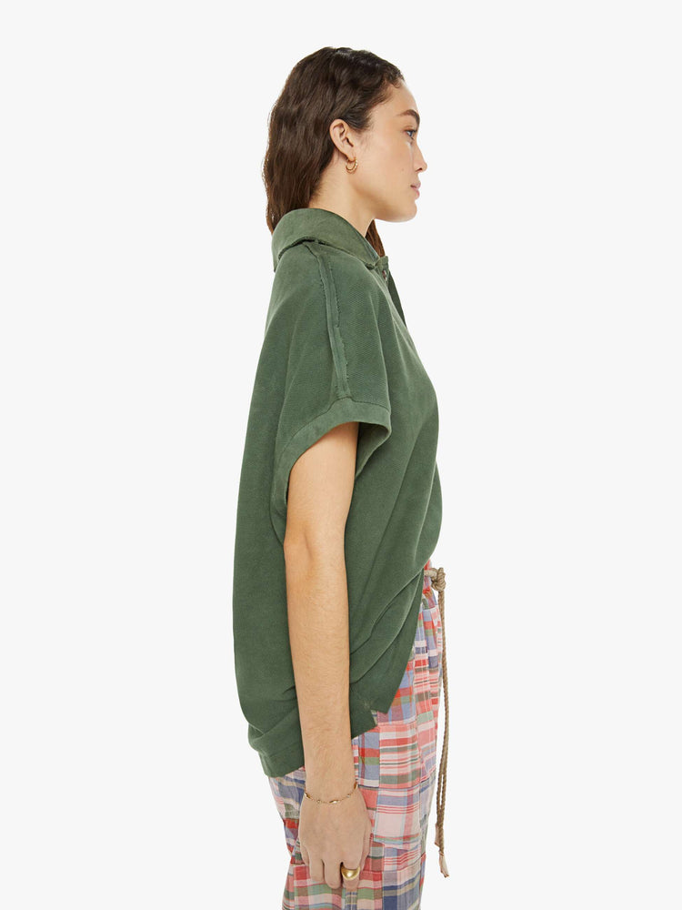 Side view of a woman in a short-sleeve polo shirt is designed with a four-button placket, a patch pocket at the hip and a loose fit in a military green.