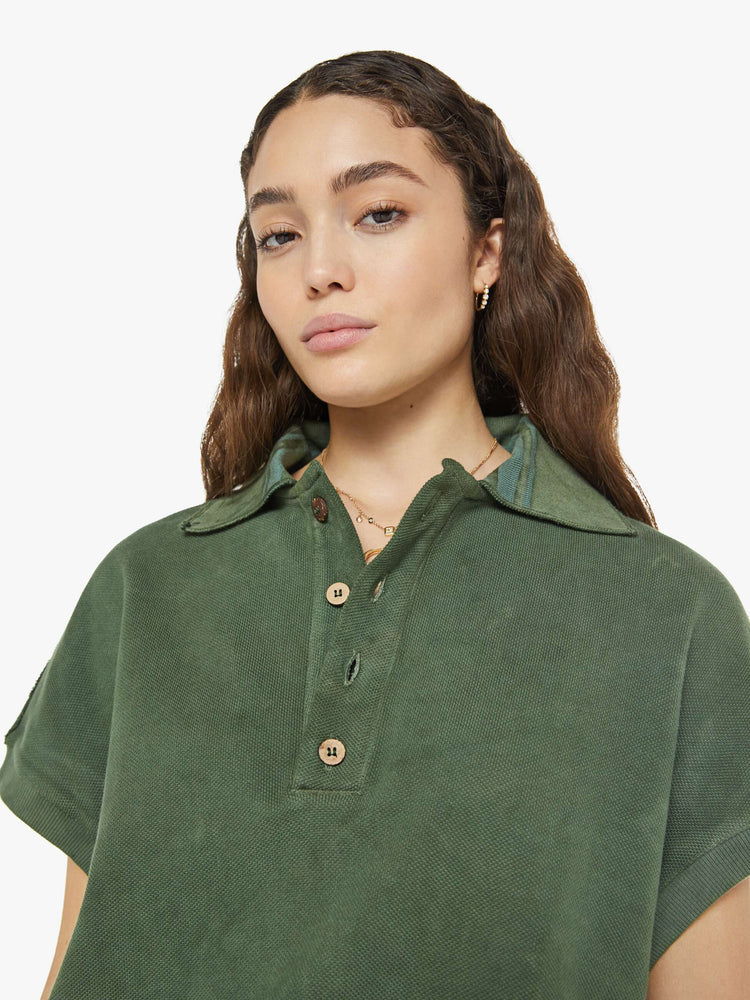 Close up view of a woman in a short-sleeve polo shirt is designed with a four-button placket, a patch pocket at the hip and a loose fit in a military green.