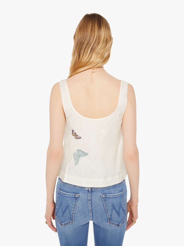 Back view of a woman in a cream sleeveless top with embroidered butterflies on the front, and features a deep scoop neck and a cropped, boxy fit.