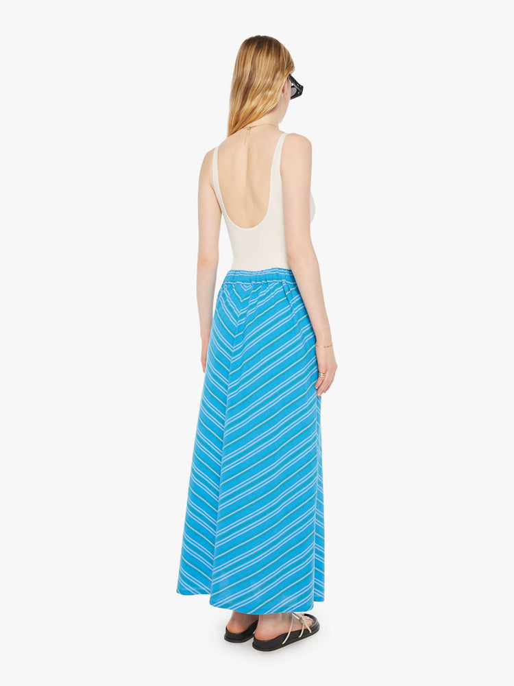 Back view of a woman in a blue with angled white stripes with a high rise, tied waistband, ankle-length hem and a loose, flowy fit.