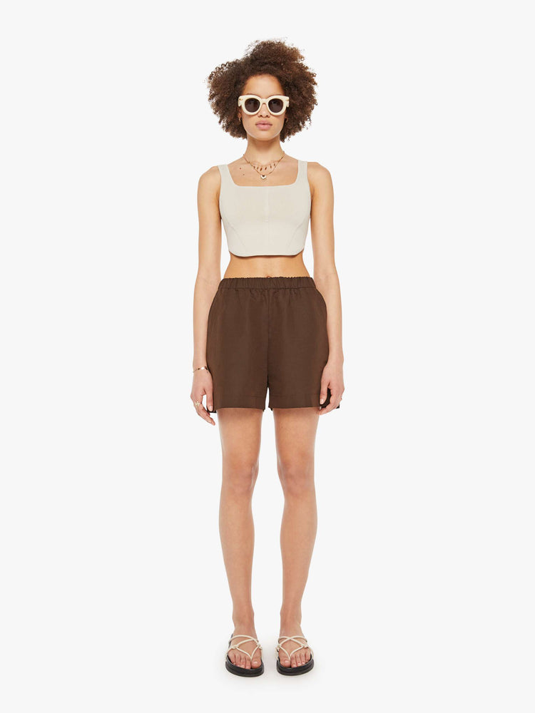 Front view of a woman in brown high rise slit pockets shorts.