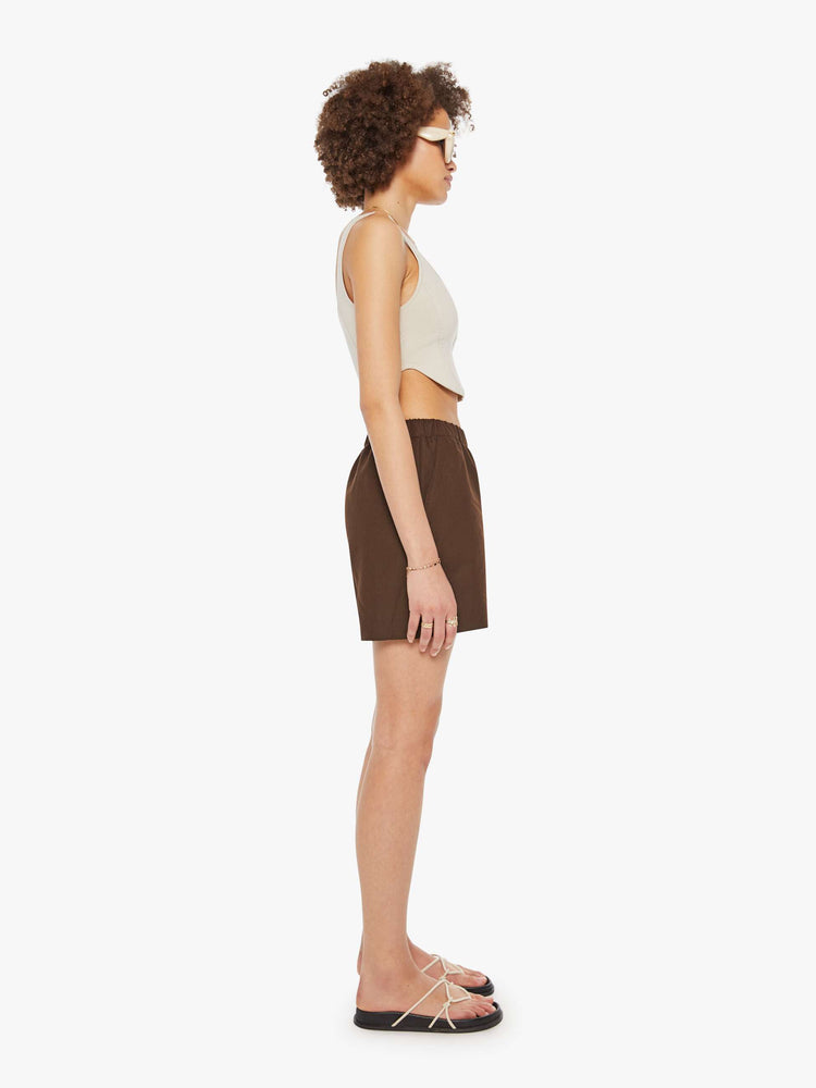 Side  view of a woman in brown high rise slit pockets shorts.