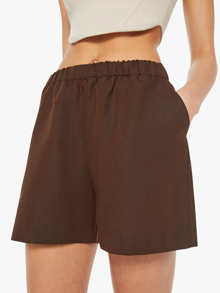 Close up  view of a woman in brown high rise slit pockets shorts.