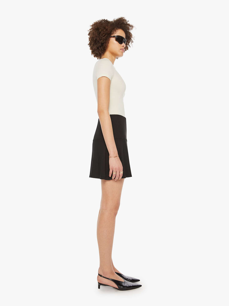 Side view of a woman in a black ribbed mini skirt.