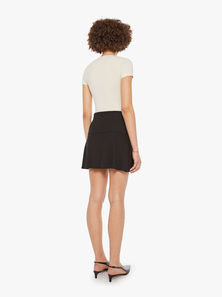 Back view of a woman in a black ribbed mini skirt.