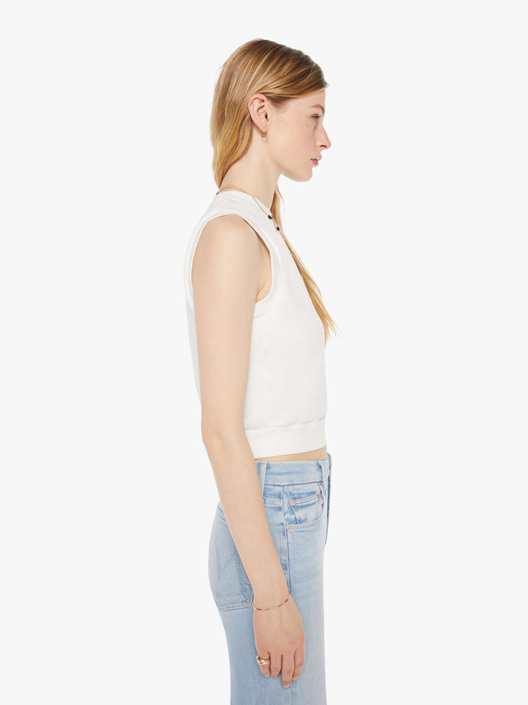 Side view of a woman in a white vest with a ribbed hem.