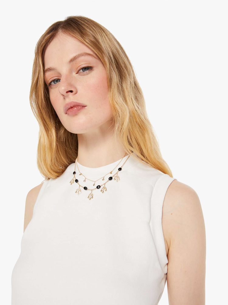 Close up view of a woman in a white vest with a ribbed hem.