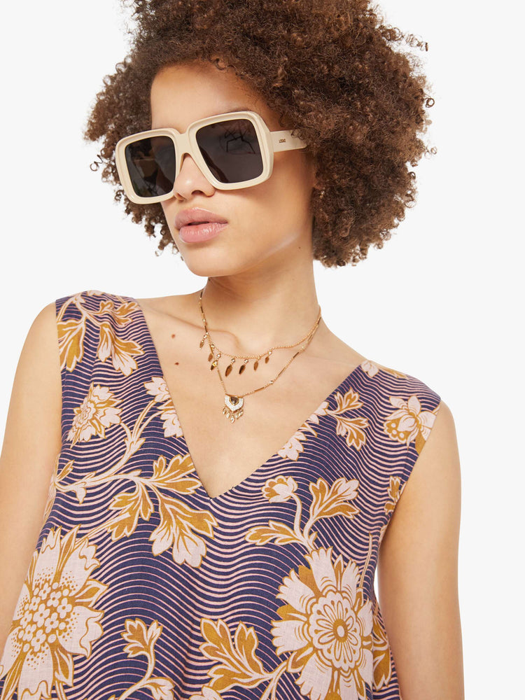 Close up view of a woman in a purple with graphic floral print dress with a V-neck, wide straps and short fit.