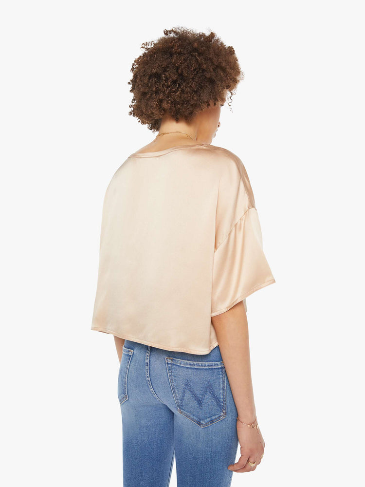 Back view of a woman in a neutral pink silk crewneck tee.