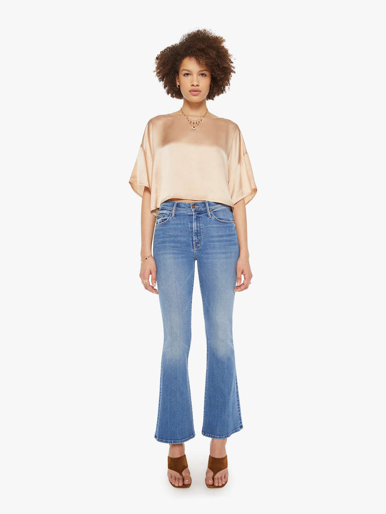 Full body view of a woman in a neutral pink silk crewneck tee.