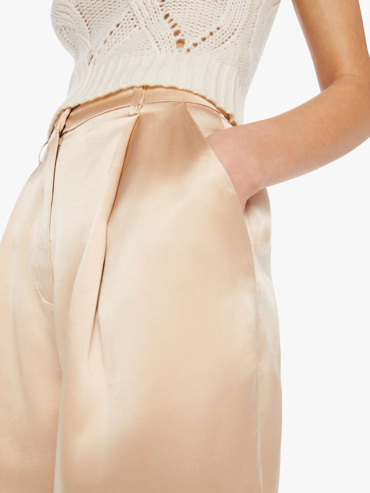 Close up view of a woman in a neutral pink high-waisted short with a pleated waistband, side slit pockets and a loose straight leg.