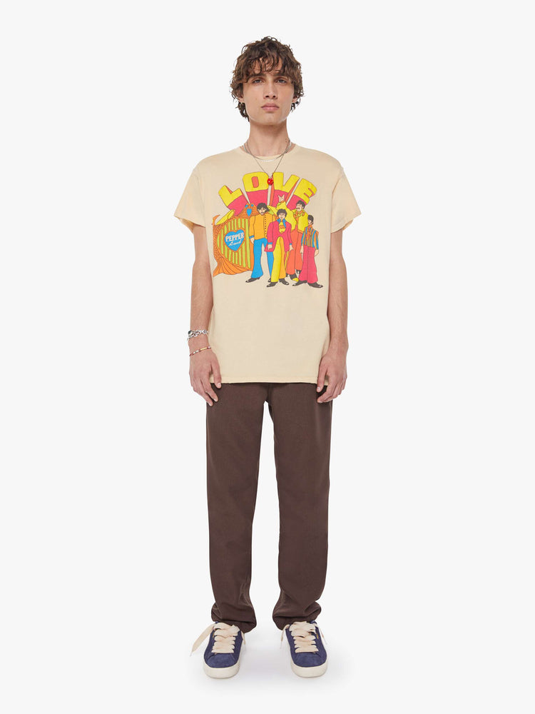 MEN full body view in a tea-stained white tee that pays homage to The Beatles with a colorful graphic on the front.
