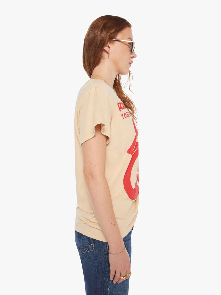 Side view of a woman in a tea-stained white tee that pays homage to the Rolling Stones' 1975 tour with the band's iconic graphic on the front.