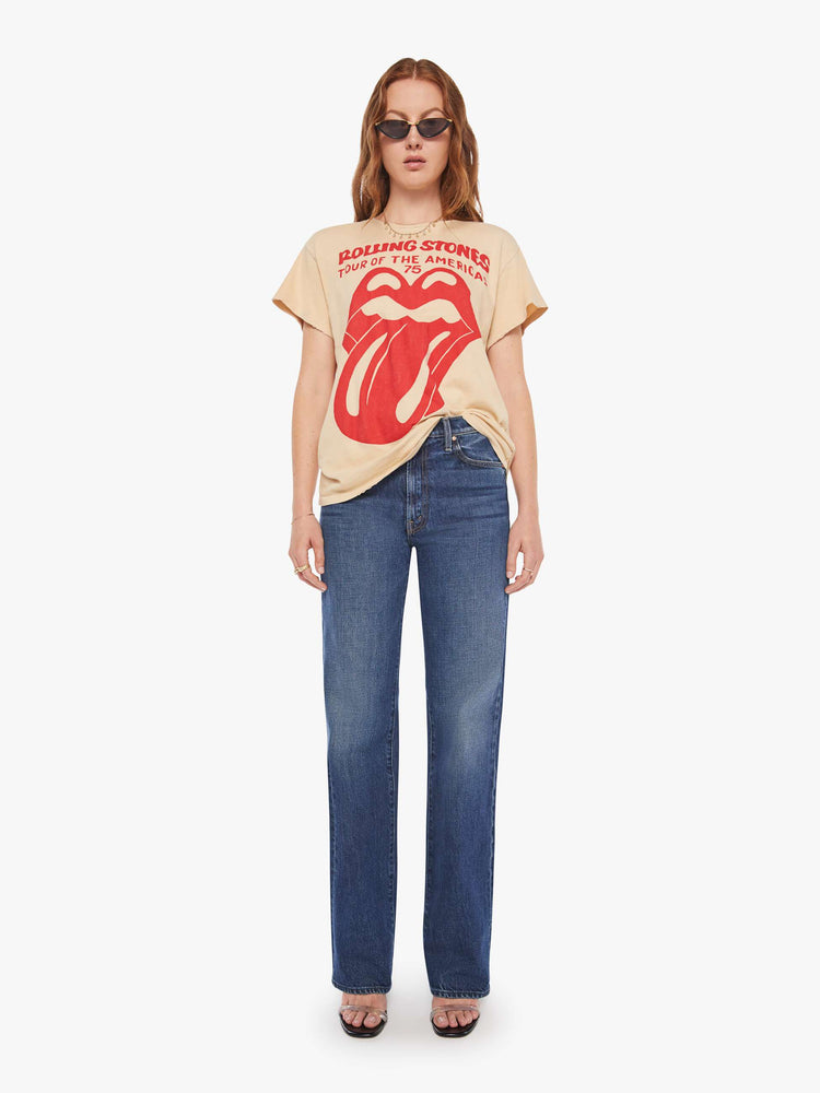 Full body view of a woman in a tea-stained white tee that pays homage to the Rolling Stones' 1975 tour with the band's iconic graphic on the front.