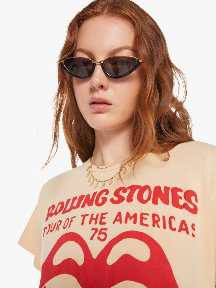 Close up view of a woman in a tea-stained white tee that pays homage to the Rolling Stones' 1975 tour with the band's iconic graphic on the front.