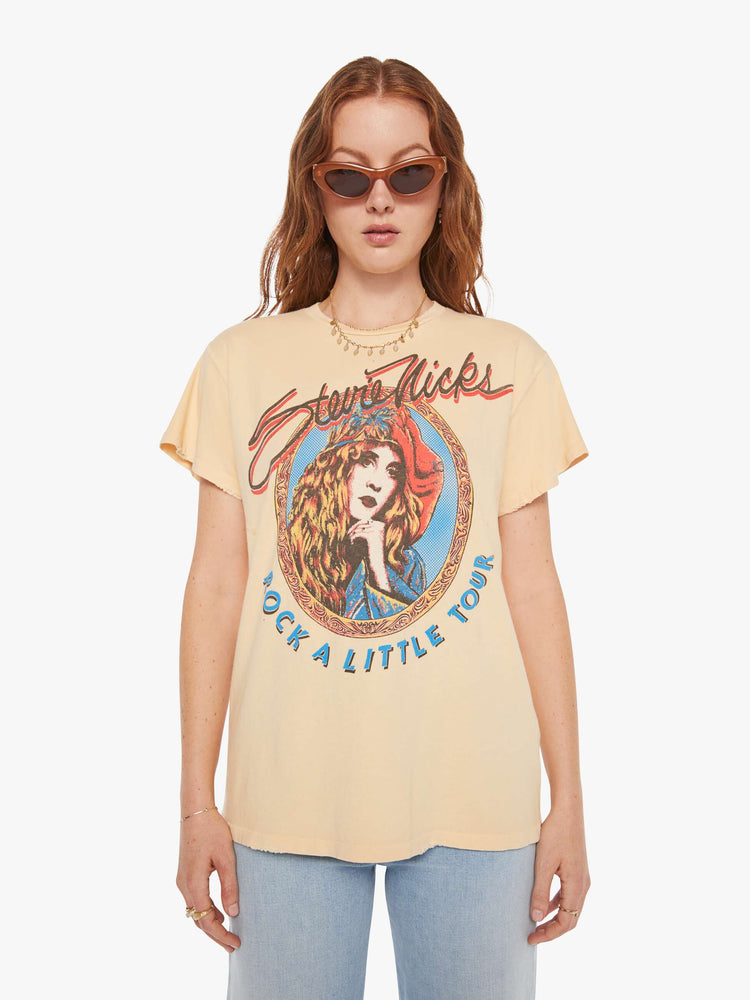 Front view of a woman in a light yellow, the tee pays homage to Stevie Nicks' Rock A Little tour with a graphic portrait on the front.