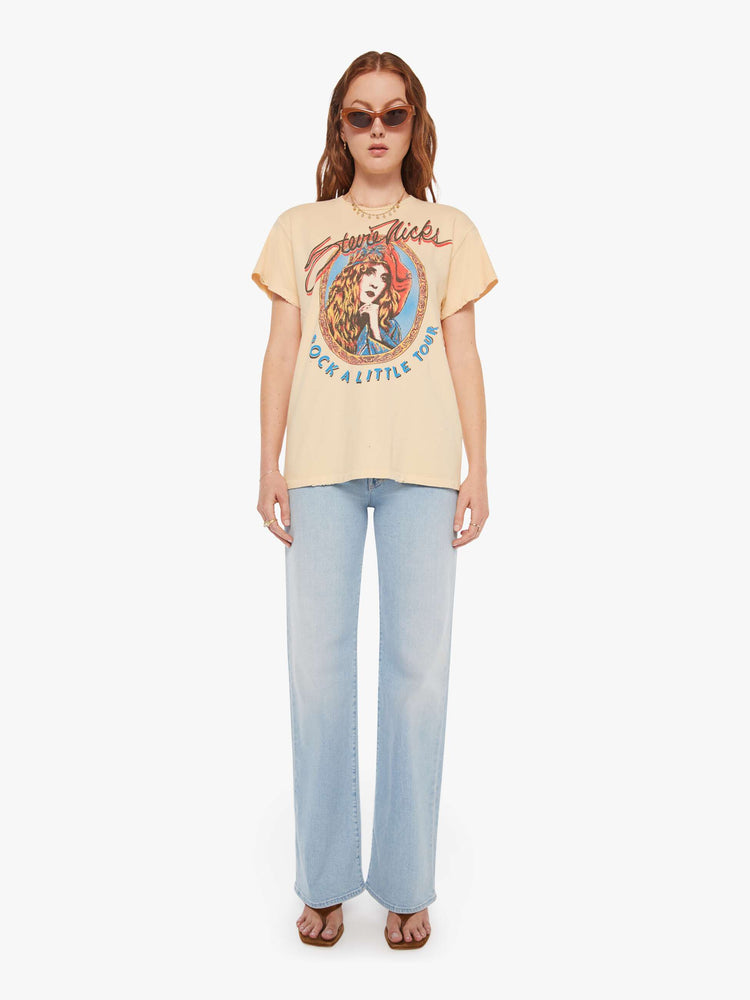Full body view of a woman in a light yellow, the tee pays homage to Stevie Nicks' Rock A Little tour with a graphic portrait on the front.