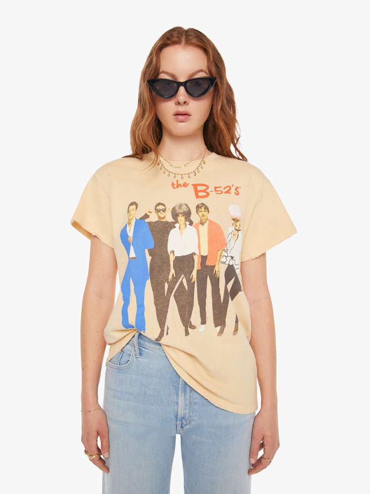 Front view of a woman in a light yellow tee that pays homage to the B-52s with a graphic portrait on the front.