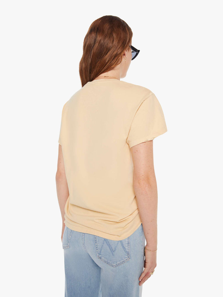 Back view of a woman in a light yellow tee that pays homage to the B-52s with a graphic portrait on the front.