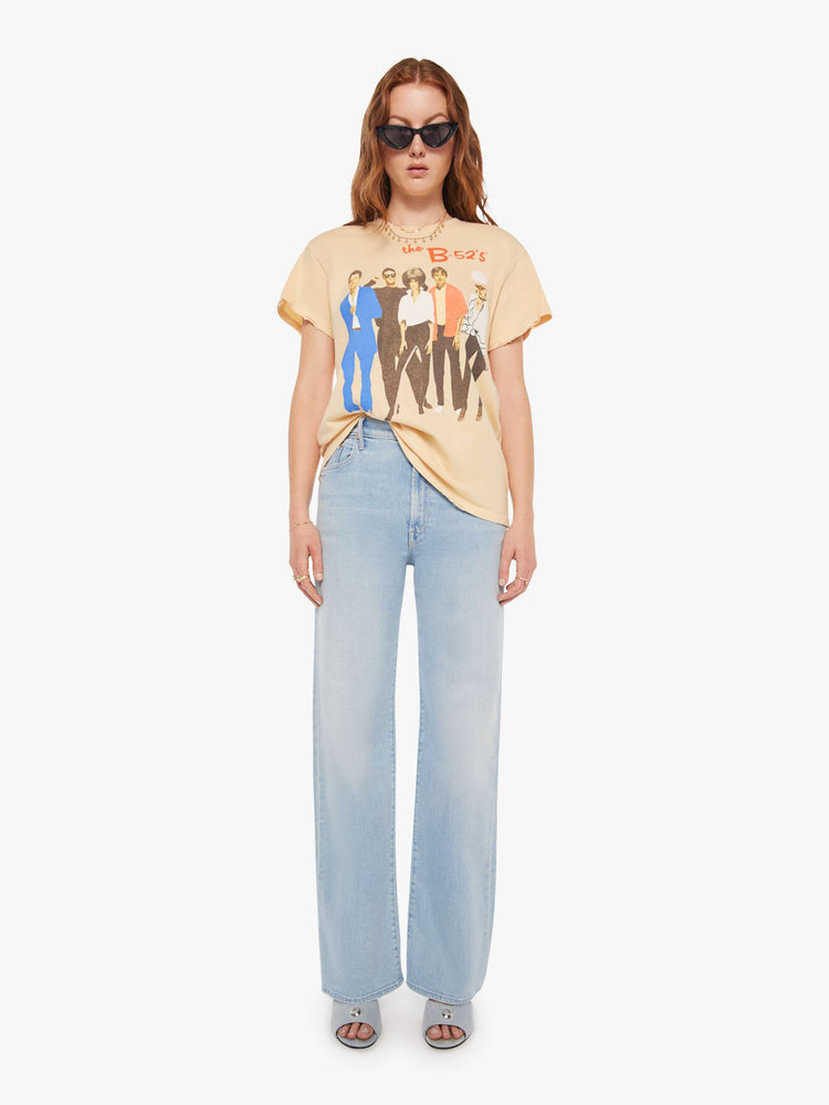 Full body view of a woman in a light yellow tee that pays homage to the B-52s with a graphic portrait on the front.