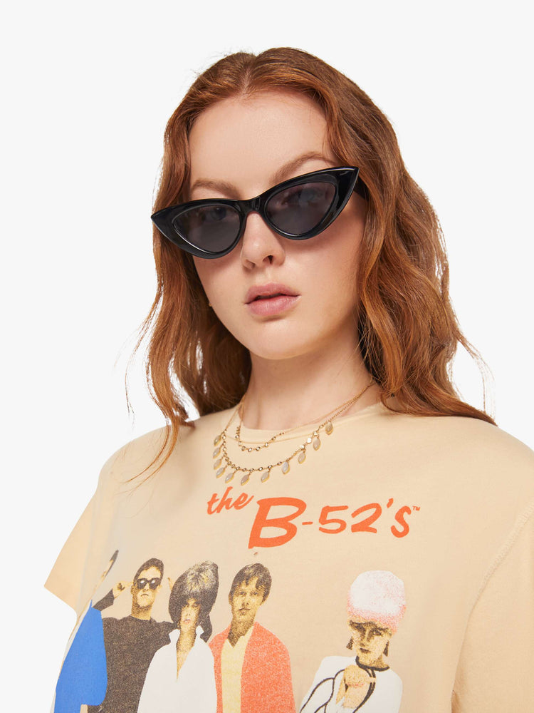 Close up view of a woman in a light yellow tee that pays homage to the B-52s with a graphic portrait on the front.