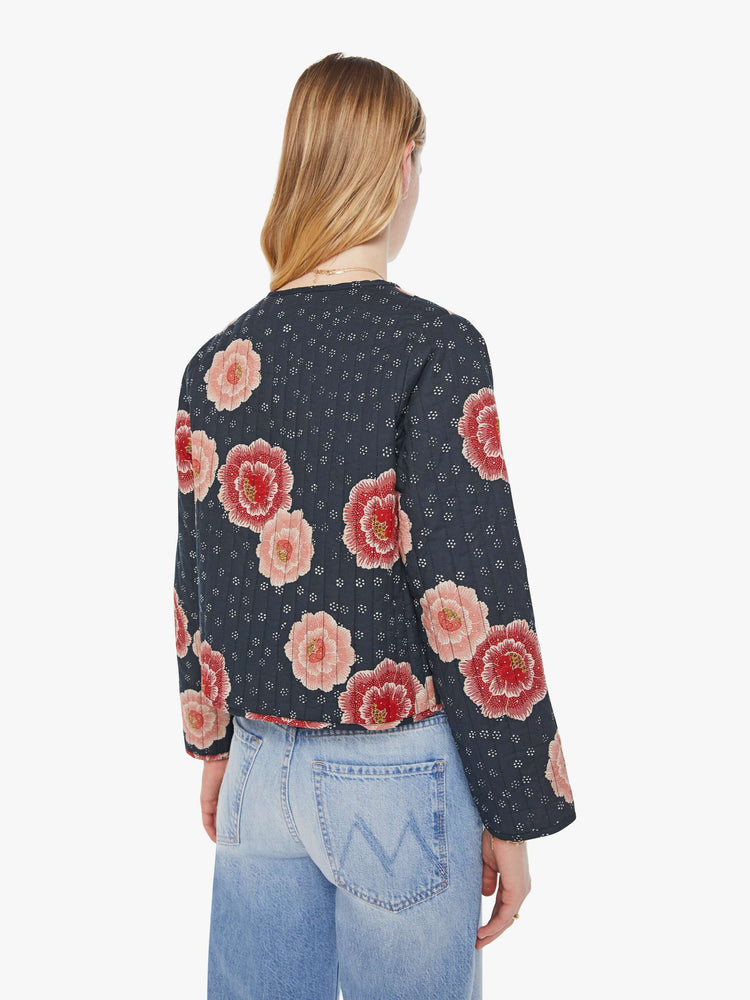 Back view of woman in a reversible jacket in maroon on one side and indigo on the other, with quilted details and a pink poppy print throughout.
