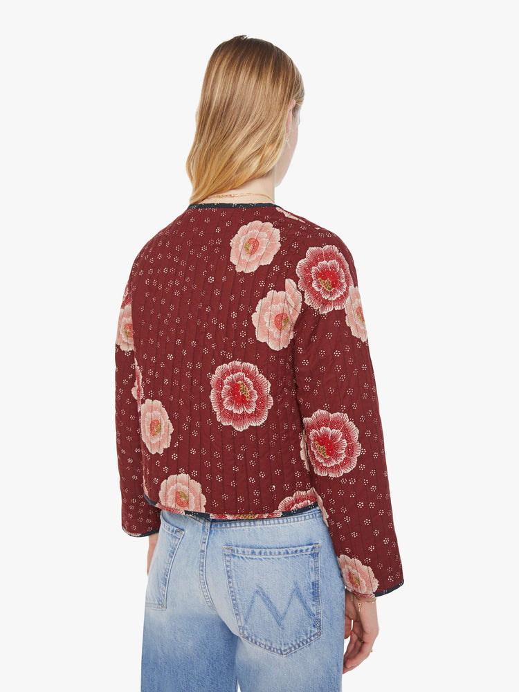 Back view of woman in a reversible jacket in maroon on one side and indigo on the other, with quilted details and a pink poppy print throughout.