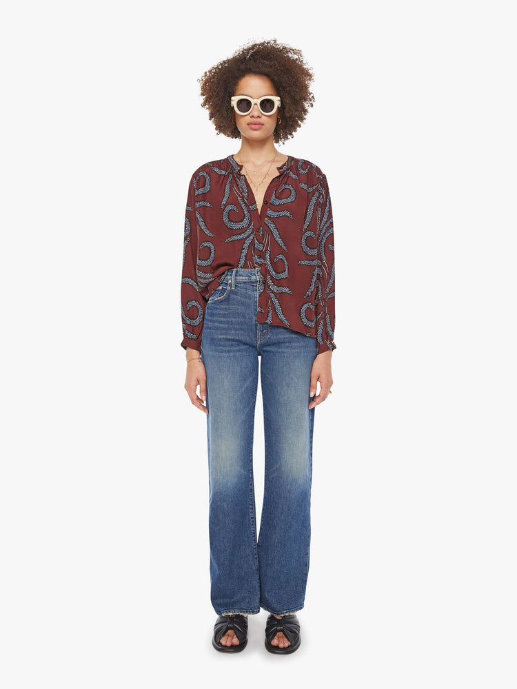 Full body view of a woman in oversized blue feather print top with a band collar, long balloon sleeves and is slightly pleated at the shoulders for a flowy fit.