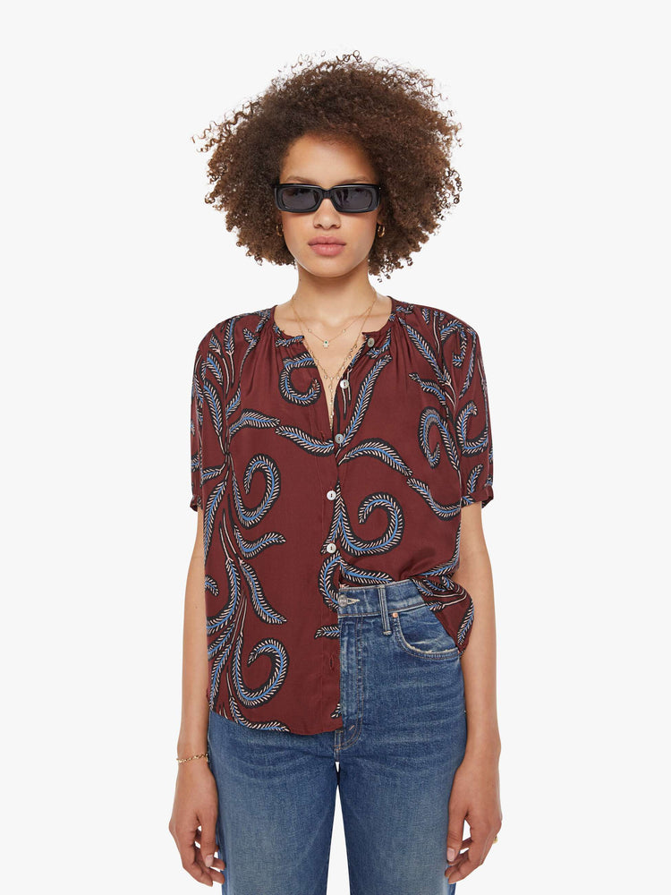 Front view of a woman in top is designed with a deep V-neck, buttons down the front, short sleeves and is slightly pleated under the collar for a loose, flowy fit.