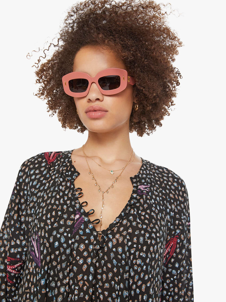 Close up view of a woman in a black with white polka dots and red swallows throughout, this maxi dress has an A-line cut for a loose, breezy feel.