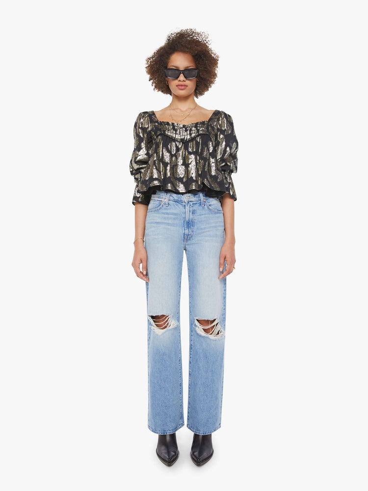 Full body view of woman top in black with a metallic graphic print, and features a square neck, elbow-length balloon sleeves with a wide ruffled hem and a cropped, flowy fit.